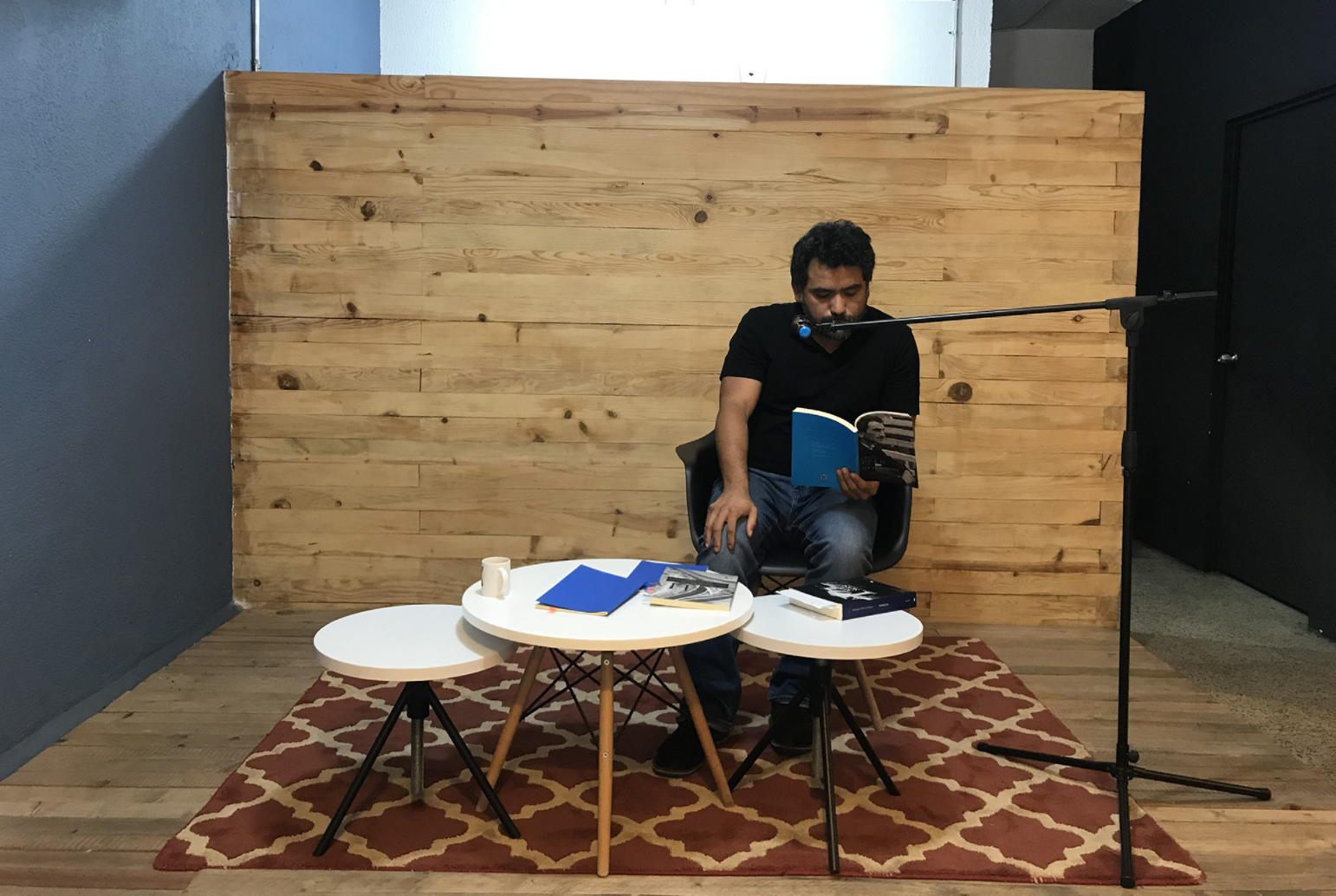 This is a picture of HUGO GARCÍA MANRÍQUEZ sitting in front of a microphone and reading from his book.